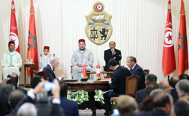 Le Président Othman Benjelloun, signant un accord avec des partenaires tunisiens, devant le roi Mohammed VI et le Président Mohamed Moncef Marzouki ainsi que SAR le prince héritier Moulay El Hassan et SAR le prince Moulay Rachid.