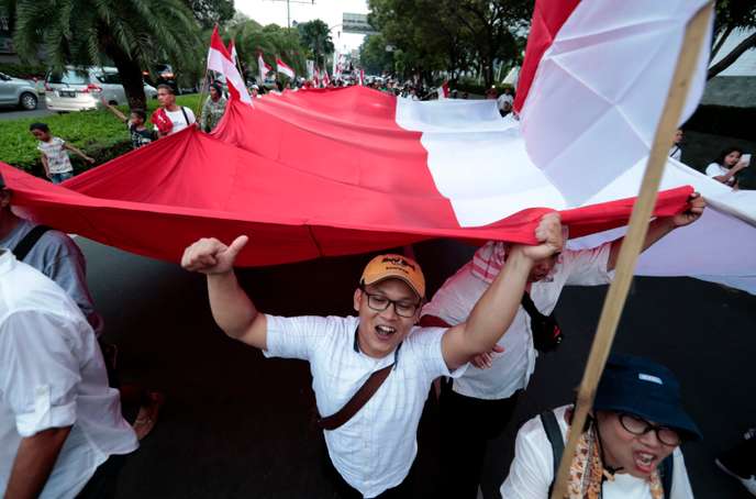 Supporters of Indonesian President Joko Widodo hold a large national Red-White flag as they celebrate during a rally in Jakarta, Indonesia, Wednesday, April 17, 2019. Widodo is on track to win a second term, preliminary election results showed Wednesday, in apparent victory for moderation over the ultra-nationalistic rhetoric of his rival Prabowo Subianto. (AP Photo/Dita Alangkara)